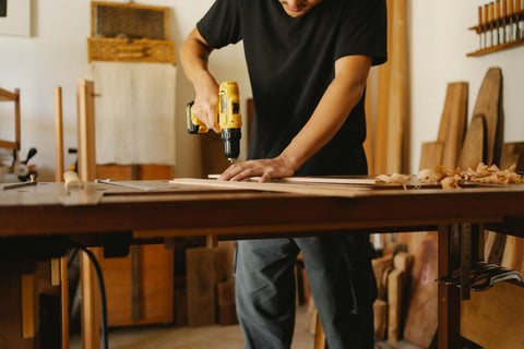 Man using drill on wood in workshop